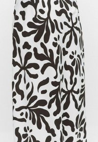 Tissu noir et blanc présentant un motif floral organique audacieux avec des formes fluides et des textures variées. Fini doux, matériau léger.