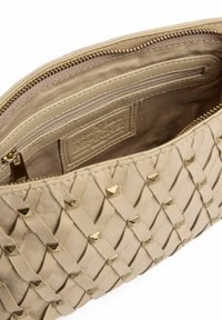 Beige leren clutch met een geweven ontwerp, voorzien van gouden piramide studs en een binnenzak met rits met beige stoffen voering.
