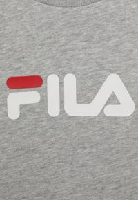 Tejido de sudadera gris con un gran logo blanco de "FILA", acentuado con una franja roja a la izquierda. Textura suave con un diseño de cuello redondo.