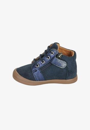 Zapatilla infantil de ante azul marino con suela marrón claro, cordones en la parte delantera, cremallera lateral y cuello acolchado para soporte del tobillo.