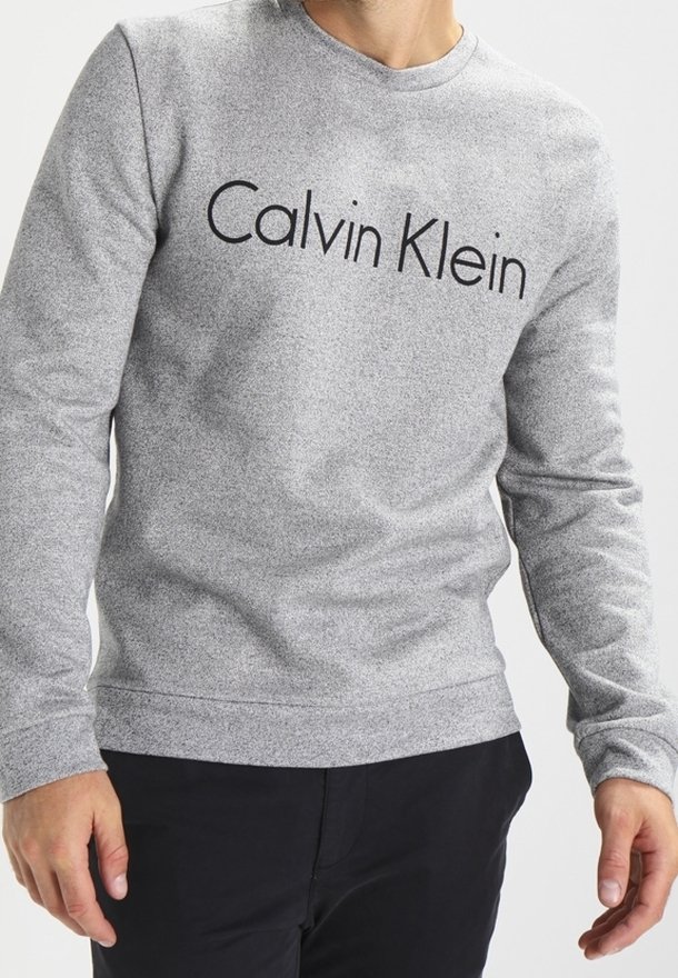 Sudadera gris con un acabado texturizado, que presenta un logotipo negro de "Calvin Klein" en el pecho, cuello redondo y puños acanalados.