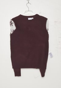 Bordeaux ärmlös tröja med ribbad nederkant, med vita och mönstrade stickade sidor. Tagg synlig i nedre högra hörnet.