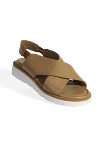 Sandales en cuir tan avec des straps entrecroisés, un talon ouvert et une semelle en caoutchouc blanche. Le design présente une texture lisse et une apparence minimaliste.