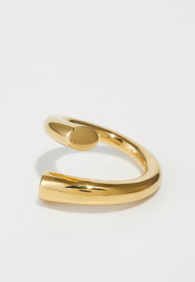 Goldfarbener Metallring mit einer glatten, polierten Oberfläche; verfügt über ein gedrehtes Design, bei dem ein Ende gebogen und das andere breiter und abgerundet ist.