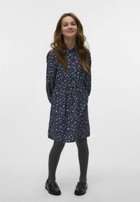 Abito a stampa floreale in blu navy con colletto con bottoni e vita elastica. Collant grigi e mocassini neri completano l'outfit.