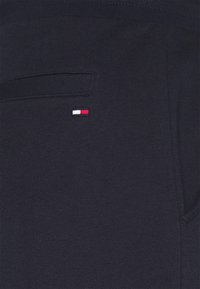 Mörkblått stickat tyg med en liten patch i röd, vit och blå. Har en ficka och en mjuk textur.