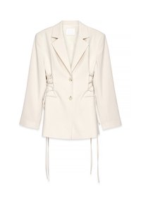Blazer de color crema con un corte entallado, cierre de doble botón y detalles laterales con cordones. Presenta hombros estructurados y mangas largas.