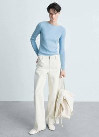 Maglione azzurro chiaro a coste a maniche lunghe, pantaloni crema a gamba larga, sneakers bianche e borsa a rete beige. Tessuto morbido e vestibilità rilassata.