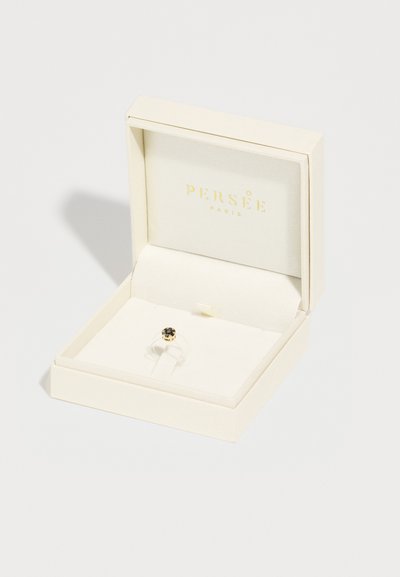 White jewelry box with soft interior, holding a ring featuring a black stone in a gold setting. Brand name "PERSÉE PARIS" in gold text on lid.