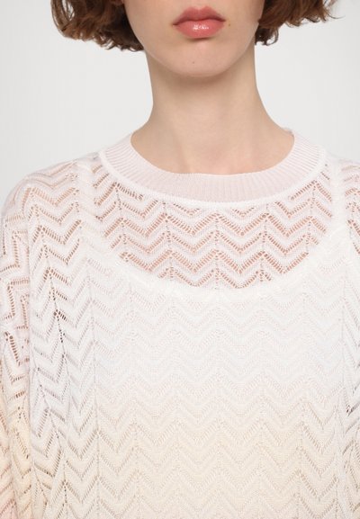 Pulover tricotat cu un model în zigzag, în culori gradient deschise de la alb la roz pal, cu guler rotund și țesătură texturată.