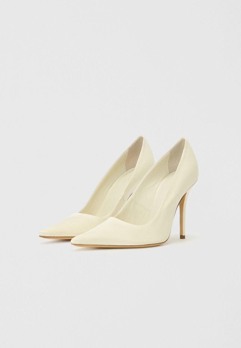 Helle gelbe High Heels mit spitzer Zehe und glattem, mattem Finish. Schlanker Stiletto-Absatz mit einem subtilen goldenen Akzent. Innenbeleuchtung.