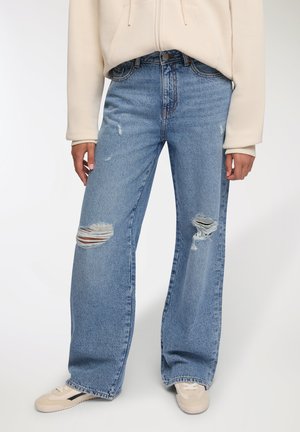 Jeans in denim azzurro chiaro con un'ampia gamba, caratterizzati da grandi strappi alle ginocchia, lavaggio medio e un classico design a cinque tasche.