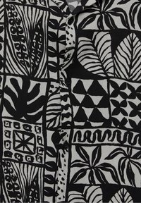 Chemise à manches courtes noire et grise avec un motif de feuilles et géométrique. Tissu texturé avec fermeture par boutons. Motifs abstraits distinctifs.