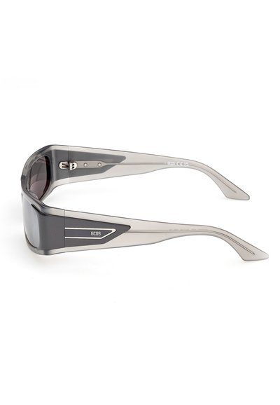 Lunettes de soleil rectangulaires transparentes grises avec des verres foncés et le logo GCDS sur les branches, vues de profil sur un fond blanc.