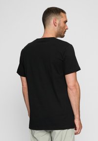 Sort bomulds t-shirt med klassisk rund hals og korte ærmer, med en afslappet pasform og minimal detaljering på ryggen.