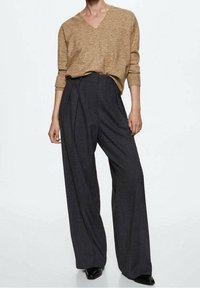 Pull beige à col en V en tissu doux, associé à un pantalon gris foncé taille haute à jambes larges. Les deux pièces ont une coupe décontractée.