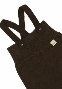 Braune gestrickte Latzhose mit gerippten Trägern und Bund. Mit Knopfdetails und einem kleinen Stoffetikett. Weiche Textur, ohne Muster.