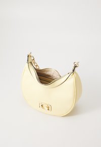 Sac à main en cuir jaune avec une forme courbée, quincaillerie dorée, fermeture zippée et une anse en chaîne. L'intérieur présente une doublure en tissu clair et des compartiments.