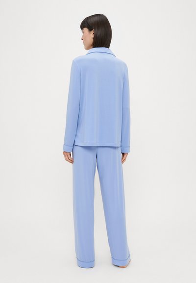 Conjunto de pijama azul claro com mangas longas com punhos e calças largas, feito de um tecido liso e macio, com um colarinho clássico.