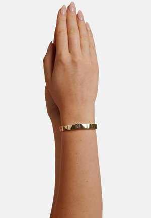Gold bracelet an einem Handgelenk, mit einem segmentierten Design, einer glatten Textur und einem zentralen Akzentdetail.