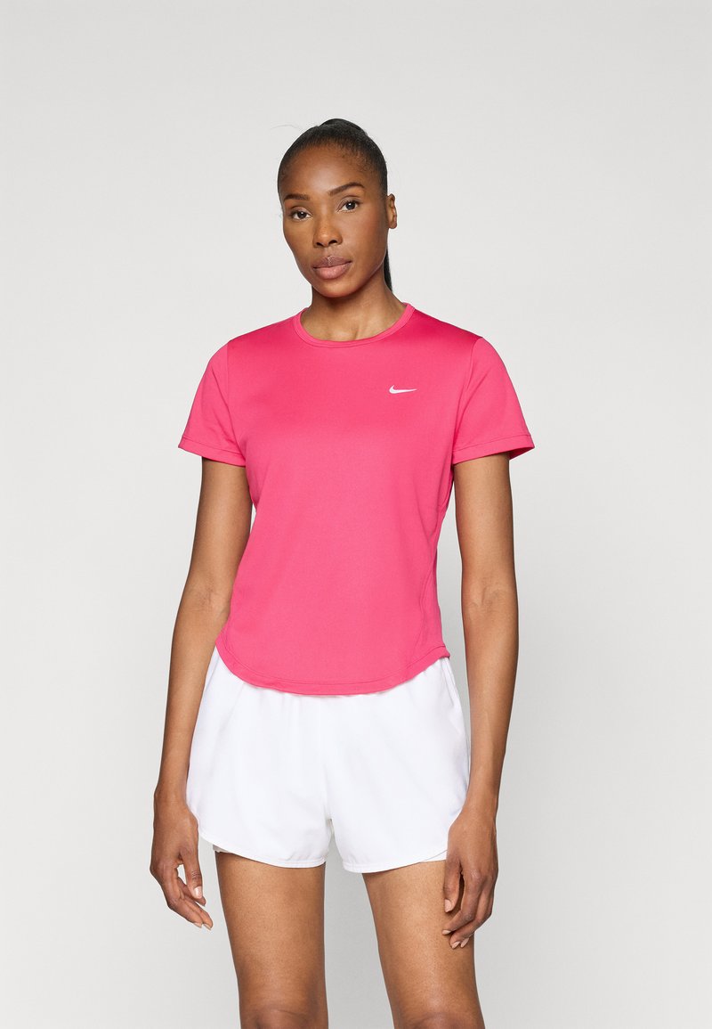 Tricou sportiv roz cu mâneci scurte și guler rotund; are un mic logo alb Nike pe piept. Modelul poartă pantaloni scurți albi.