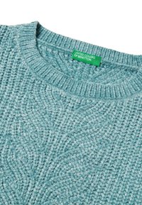 Tyrkysový texturovaný svetr s žebrovaným výstřihem a složitým vzorem. Štítek nese nápis "United Colors of Benetton" na zeleném označení.