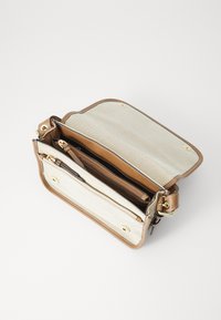 Sac à main en cuir marron avec un intérieur en tissu beige clair, présentant une poche zippée et des accessoires en métal doré. Ouvert avec plusieurs compartiments.