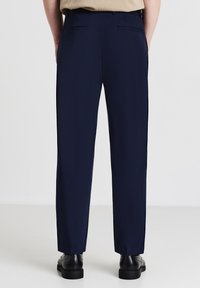 Pantaloni navy con un design a gamba dritta, dotati di due tasche posteriori e un cinturino strutturato. Realizzati in un tessuto morbido e leggero.