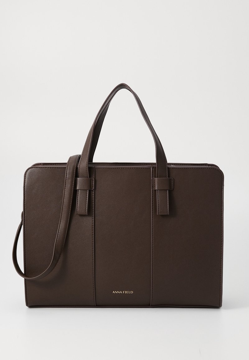 Sac à main rectangulaire marron foncé avec deux poignées supérieures, une bandoulière et le logo "ANNA FIELD" en or au centre devant.