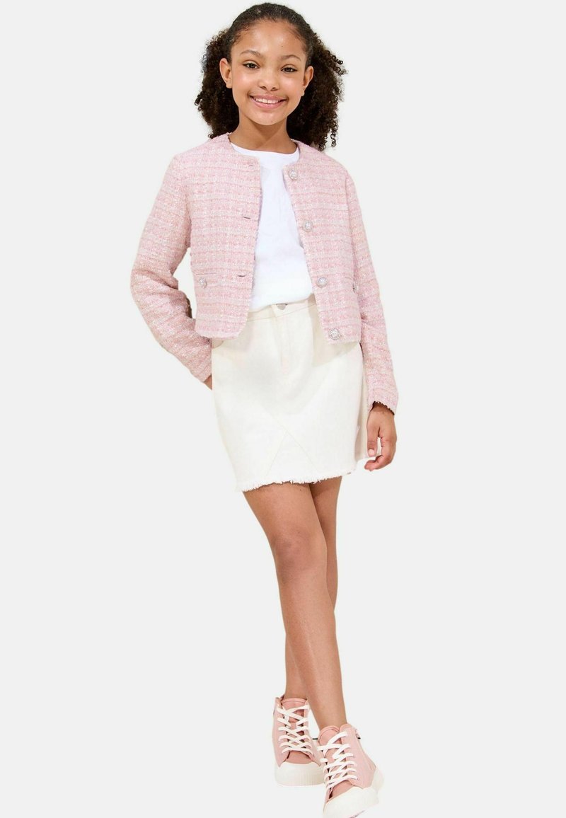 Rosa Tweedjacke mit rundem Halsausschnitt und Knopfverschlüssen, kombiniert mit einem weißen T-Shirt und einem cremefarbenen Minirock. Rosa High-Top-Sneaker.