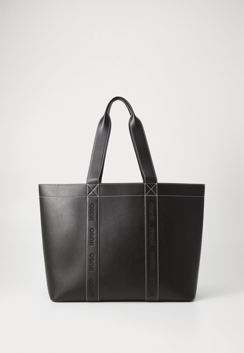 Svart läder totebag med två robusta handtag, som har präglad logotyp och kontrasterande vit sömnad längs sömmarna.