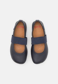 Scarpe Mary Jane in pelle blu navy con cinturino elastico, punta rotonda, soletta marrone e logo rosso. Texture liscia e design semplice.