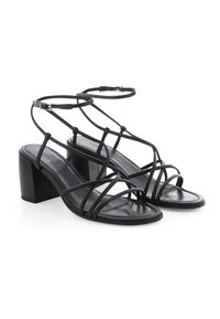 Schwarze Riemchensandalen mit Blockabsatz, die schlanke Riemen, ein schlankes Design und ein glattes Leder-Finish aufweisen.
