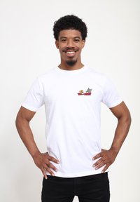 Hvid cotton t-shirt med en flerfarvet "Tom og Jerry" grafik broderet på brystet. Korte ærmer og afslappet pasform.