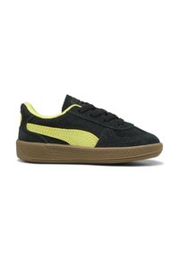 Sneaker in suede nero con accenti giallo neon e suola in gomma marrone. Presentano un design con lacci e pannelli laterali testurizzati per maggiore grip.