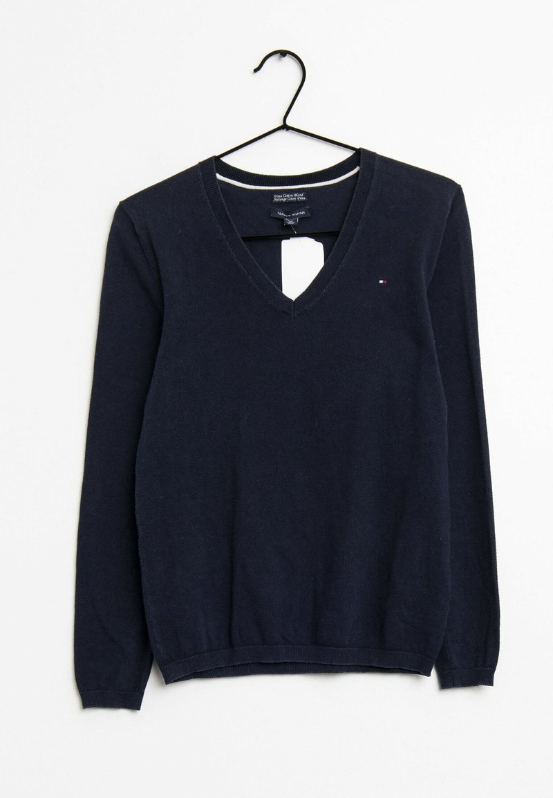 Pull bleu marine foncé à col en V et manches longues suspendu sur un cintre noir sur fond blanc avec un petit logo sur la poitrine.