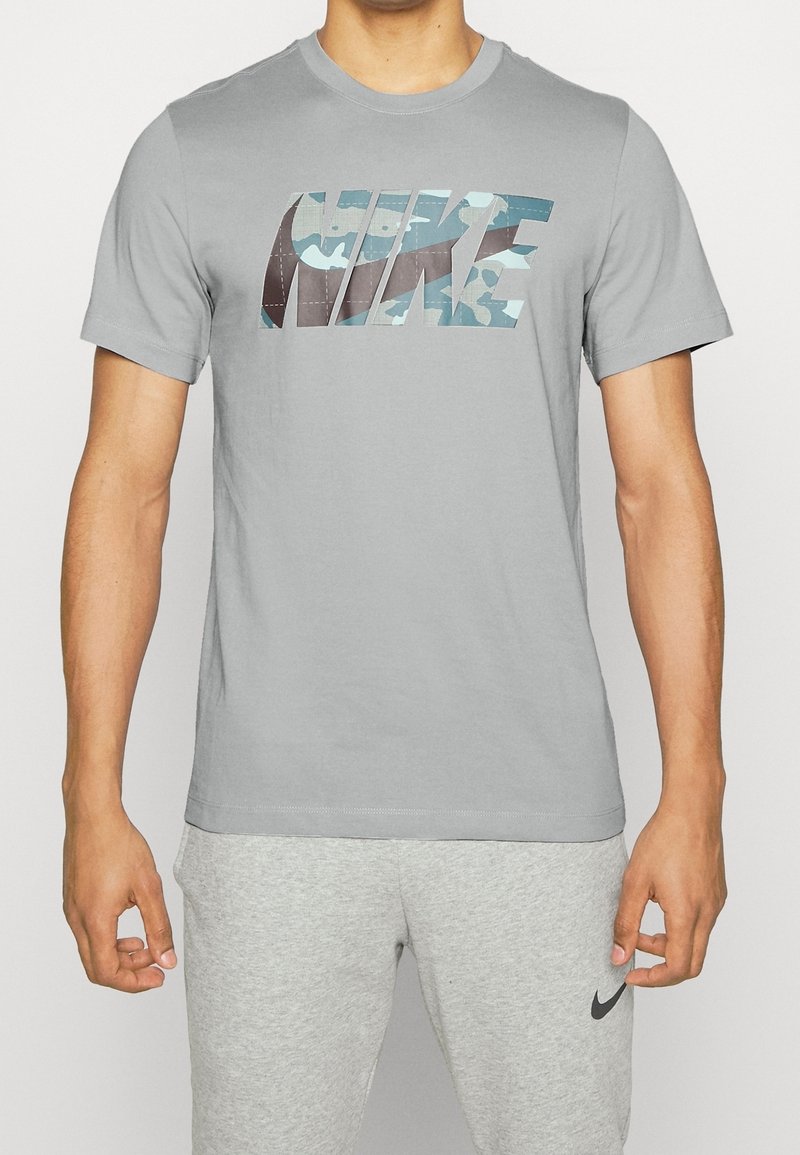 Šedé bavlněné tričko s maskáčovým logem Nike v modrých a zelených tónech. Krátké rukávy a kulatý výstřih.