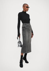 Μαύρο εφαρμοστό ζιβάγκο, γκρι τζιν μίντι φούστα με ψηλή μέση, μαύρες γόβες με λουράκι στον αστράγαλο και μια μικρή γυαλιστερή μαύρη τσάντα.