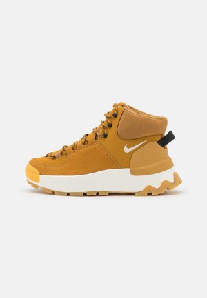 Wysokie żółte (musztardowe) buty sportowe z białym logo Nike, grubą białą podeszwą, wytrzymałą żółtą podeszwą zewnętrzną oraz czarną pętelką na pięcie.
