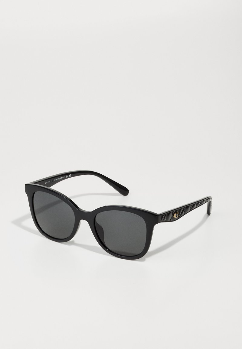 Lunettes de soleil noires en forme d'œil de chat, avec des verres gris et des branches noires texturées présentant un accent en or.