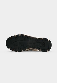 Semelle d'une chaussure de randonnée montrant une bande de roulement en caoutchouc noir avec des rainures profondes pour l’adhérence et le nom de la marque « GABOR » embossé au centre.