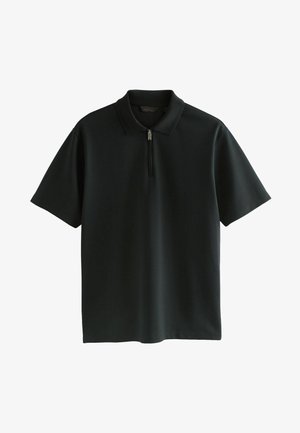Sort polo shirt lavet af blødt stof med en kort lynlås, en flad krave og korte ærmer. Glat tekstur med en afslappet pasform.