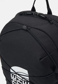 Black backpack with a textured surface, featuring a bungee cord design, and a prominent white logo on the side. Adjustable straps included.