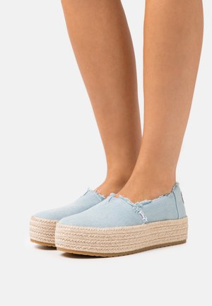 Lichtblauwe canvas espadrilles met rafelige randen, voorzien van een jute touw tussenzool en een gestructureerde rubberen buitenzool. Instapdesign.