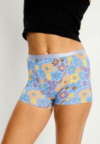 Boxers multicolores à motifs en bleu clair, comportant des fleurs, des signes de paix et des visages souriants. Tissu doux avec une taille élastique.