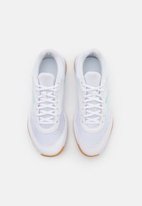 Białe buty sportowe z siateczkową cholewką, okrągłym noskiem i gumową podeszwą z brązowymi akcentami, zabezpieczone białymi sznurowadłami i oczkami.