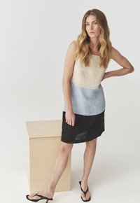 Lina segu dress neljakujulise kaelusega, millel on beeži, helesinise ja musta paneeli kombinatsioon. Helm on kergelt kõver, mis rõhutab modernset disaini.