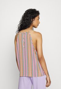 Top sem mangas de padrão multicolorido, com decote halter e detalhe em forma de buraco nas costas, feito de tecido leve e com um leve caimento.