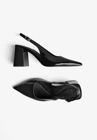Musta lakattu nahkainen slingback-kengät, joissa on terävä kärki, neliönmuotoinen tukipohja ja säädettävä nilkkahihna. Sileä, kiiltävä pinta.