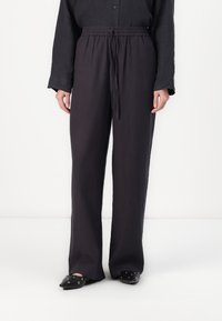 Dark, loose-fitting pants with an elastic waistband and drawstring. Made of a lightweight fabric, featuring a straight-leg design and minimal texture.